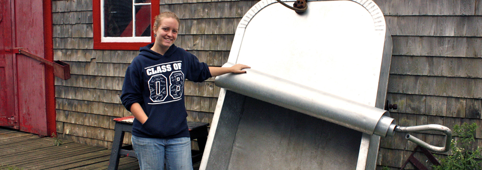 Volunteer Megan Ingalls with founder Michael Zimmer’s boat, built in the shape of a sardine can, Sardine Museum and Herring Hall of Fame