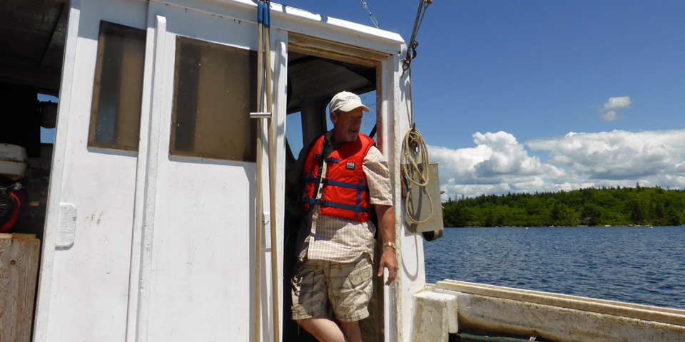 "The Oysterman", Nolan D'Eon, on his boat at Eel Lake Oyster Farm, Ste. Anne du Ruisseau, Nova Scotia 