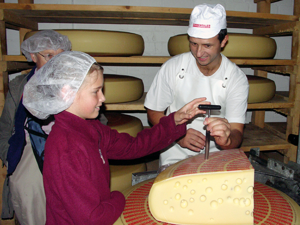 cheese master, Alfred Bieri-Meyes, shows a young visitor how to test the Emmantaler cheese for quality, Blumenstein, Switzerland